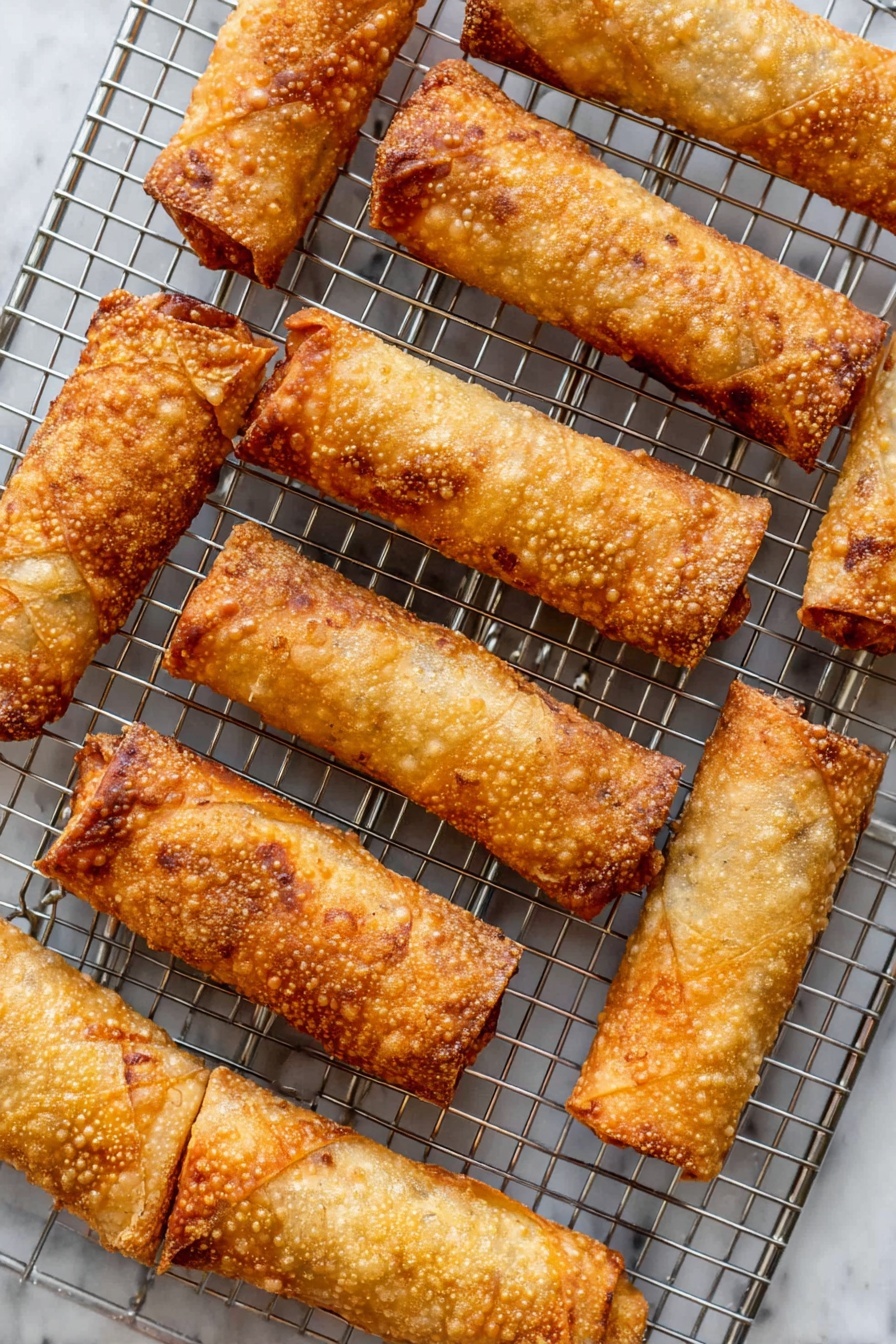 Turkey Egg Rolls with Crispy Filling, turkey egg rolls recipe, healthy egg roll ideas, easy crispy egg rolls, savory turkey appetizer - The image shows several golden brown egg rolls arranged neatly on a silver cooling rack. Each egg roll has a crispy, bubbly texture with a tightly wrapped, cylindrical shape and some have small darkened, slightly burnt edges. They sit elevated from the white marbled surface beneath, creating slight shadows below the rack. The color varies from light to medium golden, indicating they are fried to a crunchy finish. The photo taken with an iphone --ar 2:3 --v 7