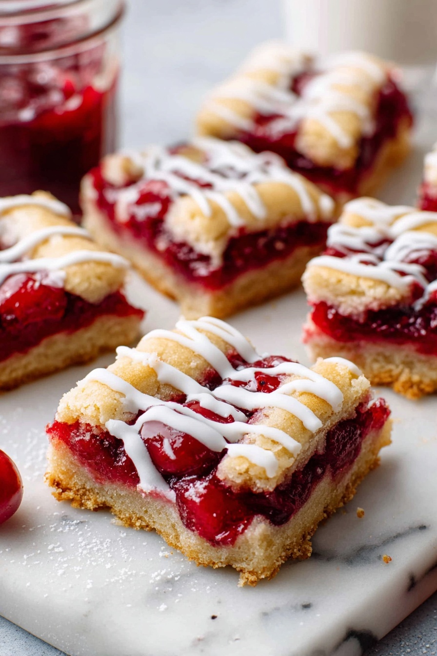 Cherry Pie Bars with Almond Glaze, cherry dessert bars, easy cherry dessert recipes, almond glaze cherry bars, fruity bar dessert - The image shows seven square cherry dessert bars arranged on a white marble cutting board and white marble surface. Each bar has three layers: a golden-brown crust on the bottom, a thick bright red cherry filling with whole cherries in the middle, and a slightly cracked golden crust on top. White icing is drizzled unevenly over all the bars. To the right of the bars is a small glass jar filled with bright red cherry topping. Below the bars is a small, clear glass bowl with white icing and a gold spoon inside it. A gray textured cloth is partially visible in the upper right corner. Photo taken with an iphone --ar 2:3 --v 7