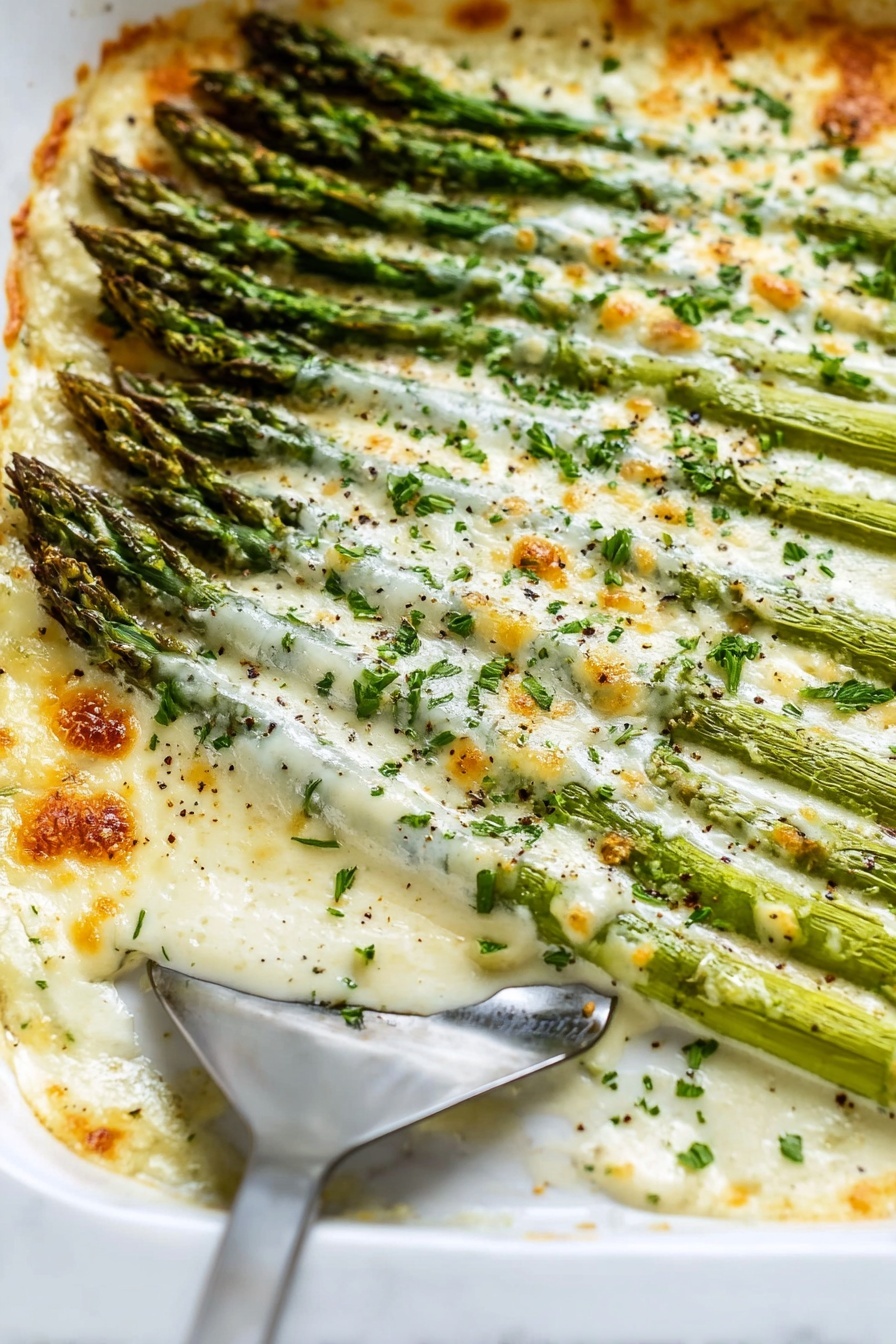 Cheesy Baked Asparagus, baked asparagus with cheese, easy asparagus side dish, healthy cheesy asparagus, simple asparagus recipes - The image shows a white rectangular baking dish filled with baked asparagus covered in a creamy, melted cheese sauce. The asparagus spears are arranged in neat parallel rows, with a layer of slightly browned, bubbly cheese on top. Small green parsley bits are sprinkled across the cheese, adding a touch of color. The edges of the cheese are golden and crisp where it has baked longer. The dish rests on a white marbled surface with a gray cloth partially visible nearby. A silver spoon is placed inside the dish near the bottom right corner, slightly lifting some asparagus and cheese. Photo taken with an iphone --ar 2:3 --v 7