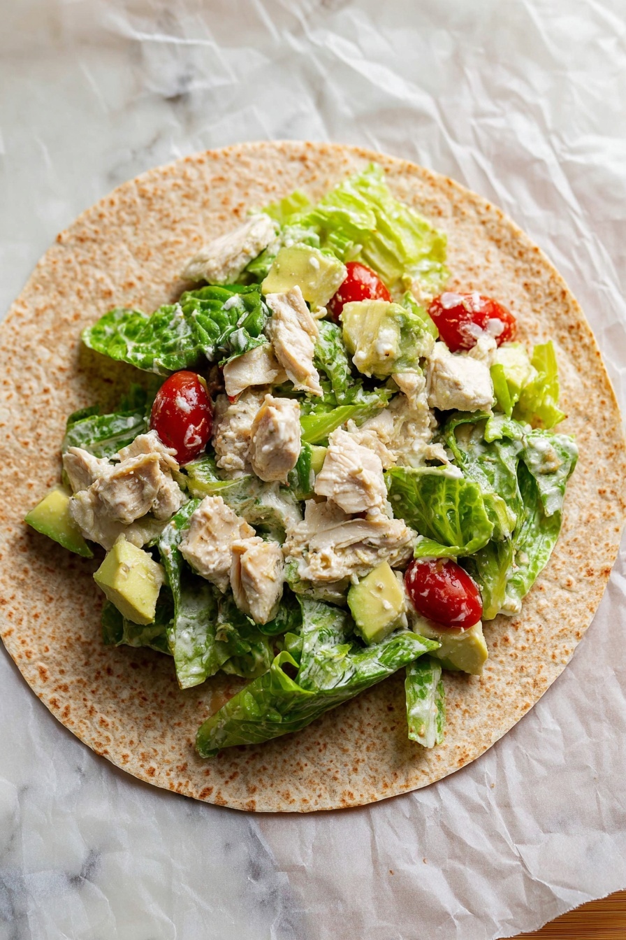 Chicken Caesar Wraps, Caesar Wraps Recipe, Easy Chicken Wraps, Healthy Chicken Wraps, Chicken Lunch Ideas - Two toasted wraps are placed on a white plate with ripple-cut potato chips scattered around them. Each wrap is cut in half, showing three layers inside: light brown chunks of chicken, green leafy lettuce, and small red tomato pieces mixed with white creamy sauce. The wraps have a slightly browned texture with darker spots from toasting. In the background, there is a second plate with more wrap halves and chips, all on a white marbled surface. A blue and white cloth with fringes lies beside the plate. photo taken with an iphone --ar 2:3 --v 7